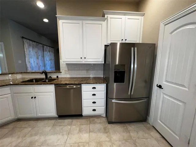 a kitchen with stainless steel appliances granite countertop a refrigerator and a sink