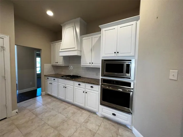 a kitchen with granite countertop white cabinets and refrigerator