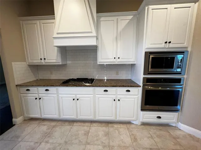 a kitchen with stainless steel appliances granite countertop white cabinets granite counter tops and a window