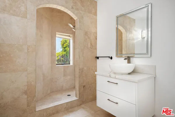 a bathroom with a granite countertop sink a mirror and shower
