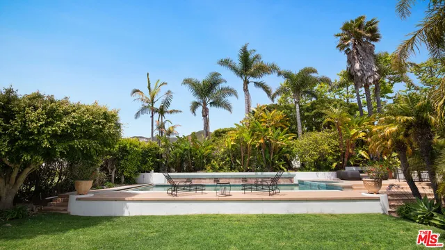 a view of house with swimming pool and trees in the background