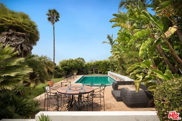 a backyard of a house with table and chairs potted plants
