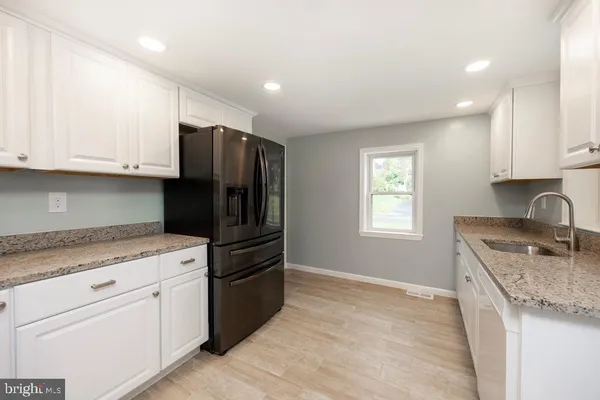 a kitchen with granite countertop white cabinets and stainless steel appliances
