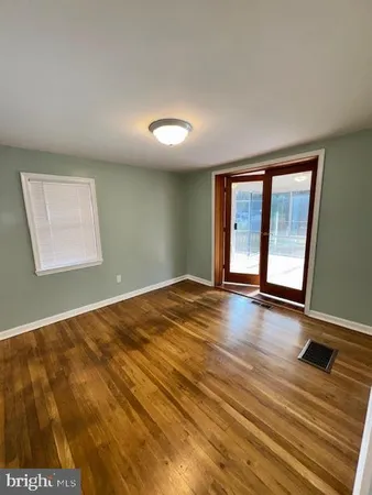 a view of an empty room with window and wooden floor