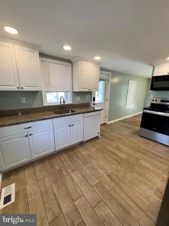 a large kitchen with stainless steel appliances granite countertop a sink and cabinets