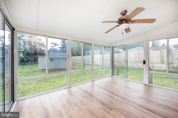 an empty room with wooden floor and a ceiling fan