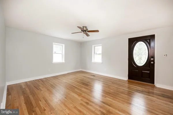 an empty room with wooden floor fan and windows