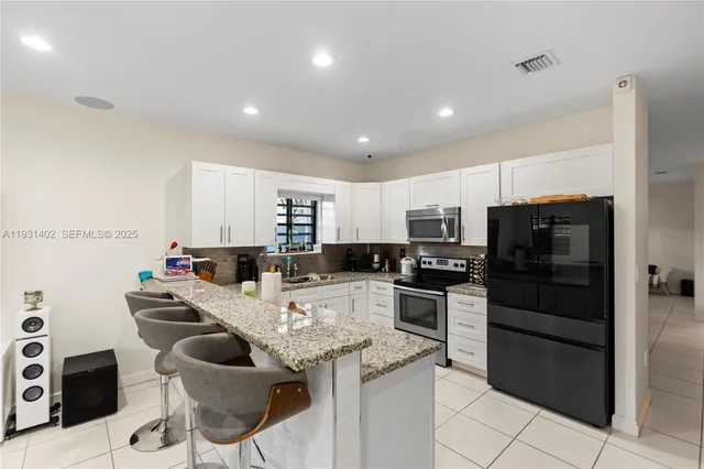 a kitchen with kitchen island white cabinets and stainless steel appliances