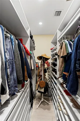 a view of walk in closet with clothes and shoes
