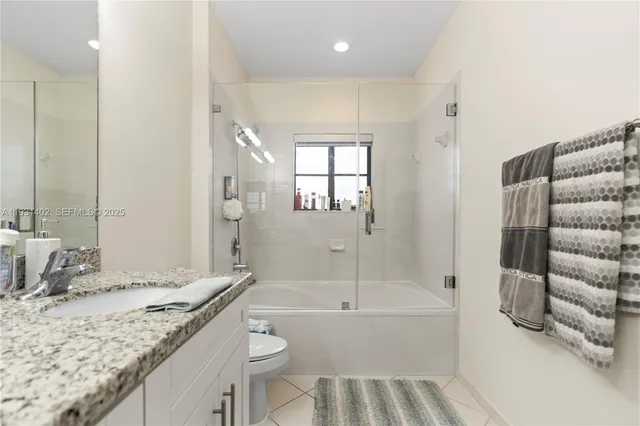 a bathroom with a granite countertop sink a toilet and a large mirror