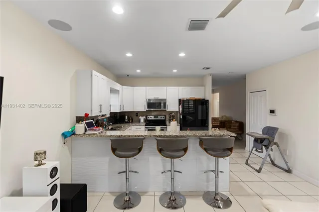 a kitchen with a dining table chairs sink and white cabinets