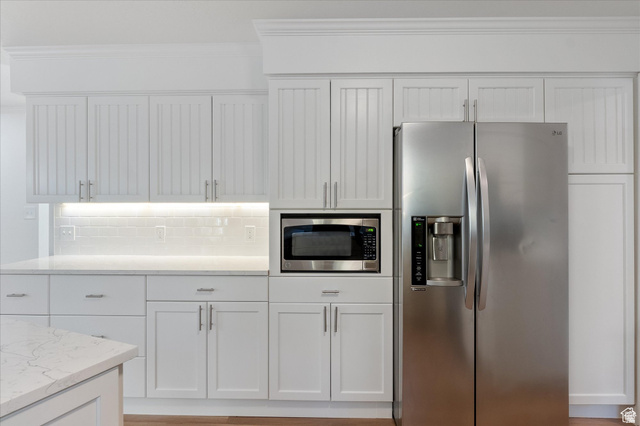 2078 Spring Oaks Drive Springville, UT 84663 - Photo 20 of 40 Kitchen featuring stainless steel appliances, white cabinets, backsplash, crown molding, and light stone countertops