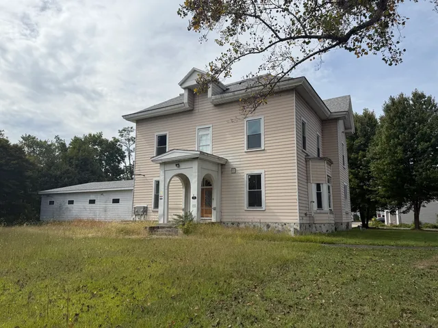 a white house that has a tree in front of it