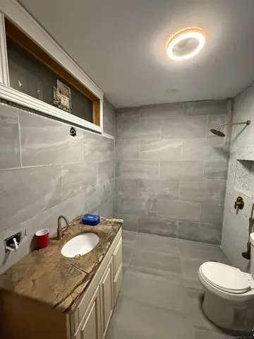 a bathroom with a granite countertop sink a toilet and shower