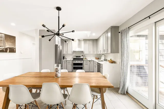a kitchen with stainless steel appliances kitchen island granite countertop a dining table chairs and a refrigerator