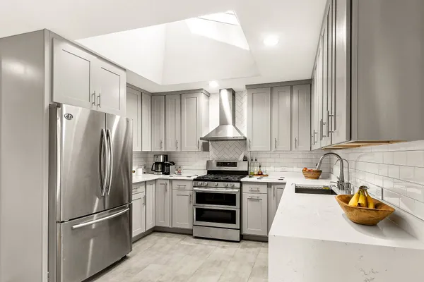 a kitchen with stainless steel appliances granite countertop a refrigerator a sink and a stove