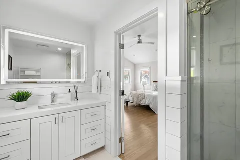a en suite bathroom with a granite countertop sink and mirror
