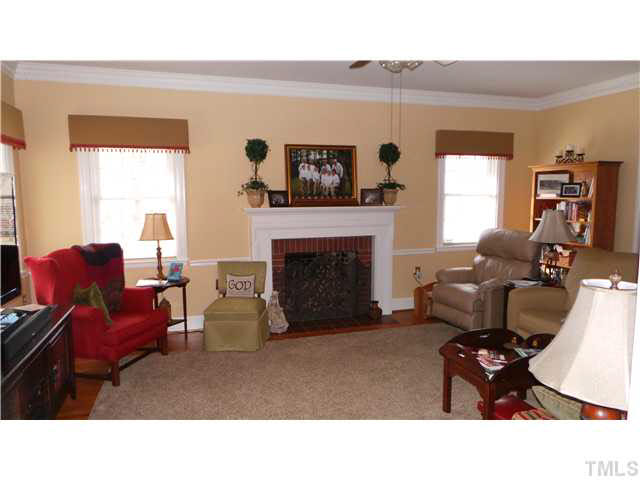 The Living Room is shown here taken from the doorway of the Dining Room.  The room is spacious as you can see with a masonry fireplace with gas logs installed.  Note the hardwood floors, the crown dental molding and ceiling fan.
