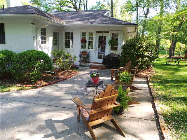 101 Forest Road Oxford, NC 27565 - Photo 21 of 25 Outside, this shows the Patio area from the driveway making a nice seating area while enjoying the outdoors. You see the door to the Sun Room as well as the back door. There will be plenty of shade from the large oak trees in the summer time.