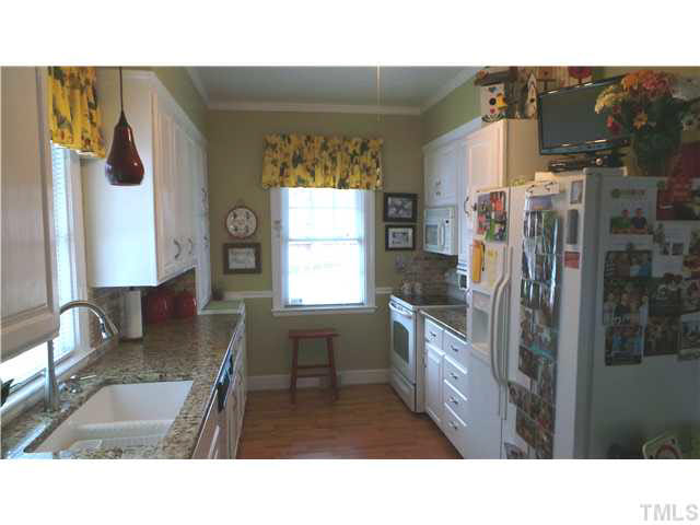 From the back door entrance, this shows the Kitchen.  Note the granite countertops, ample counter space, large double sink, beautiful cabinets, and ceiling fan.  The galley style Kitchen makes the Kitchen very efficient according to the Seller.