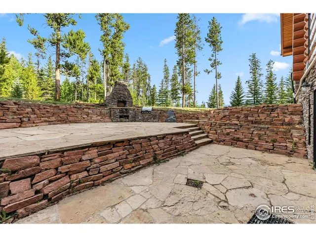 a view of a patio with dining table and chairs under an umbrella with a barbeque