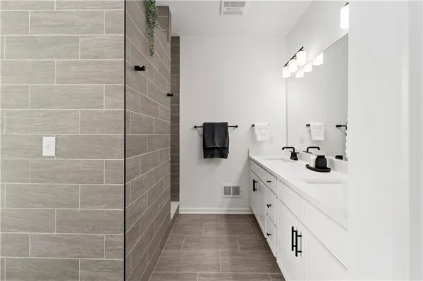 a bathroom with a double vanity sink a mirror and a shower