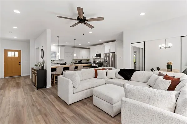 a living room with furniture kitchen area and a wooden floor