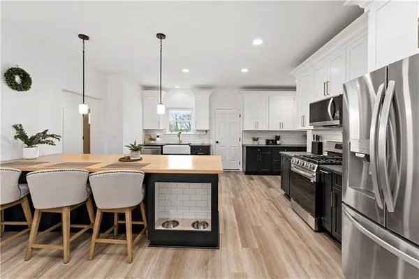a kitchen with stainless steel appliances granite countertop a sink a stove a refrigerator and island with wooden floor