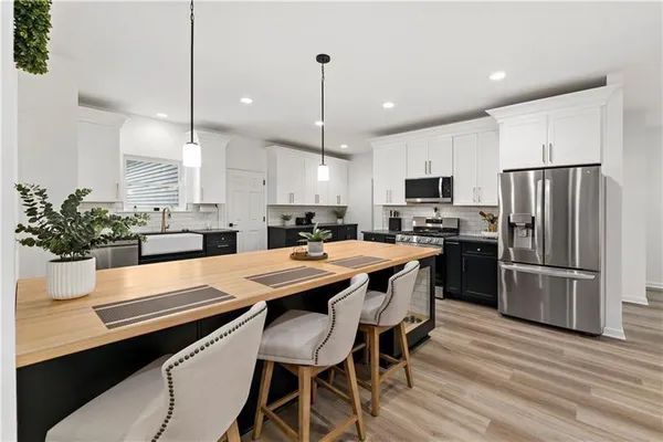 a kitchen with granite countertop a refrigerator a stove a sink a dining table and chairs with wooden floor