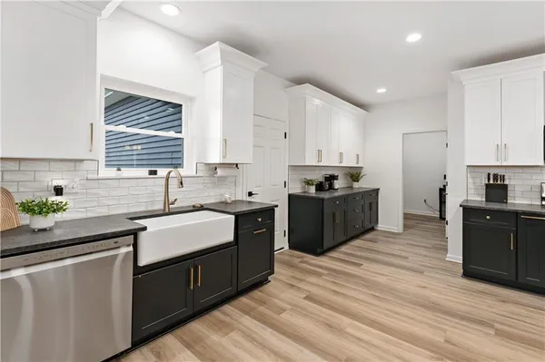 a kitchen with stainless steel appliances granite countertop a sink a stove a refrigerator with white cabinets and wooden floor