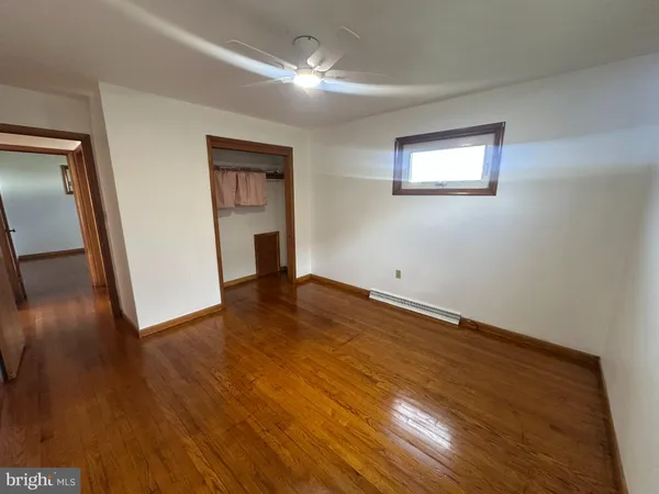 a view of empty room with wooden floor and fan