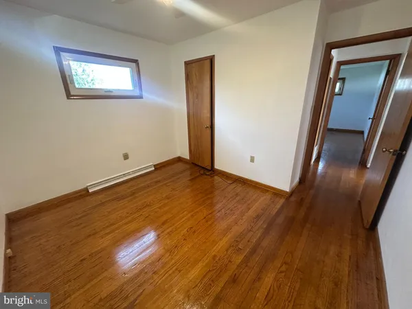 an empty room with wooden floor and mirror