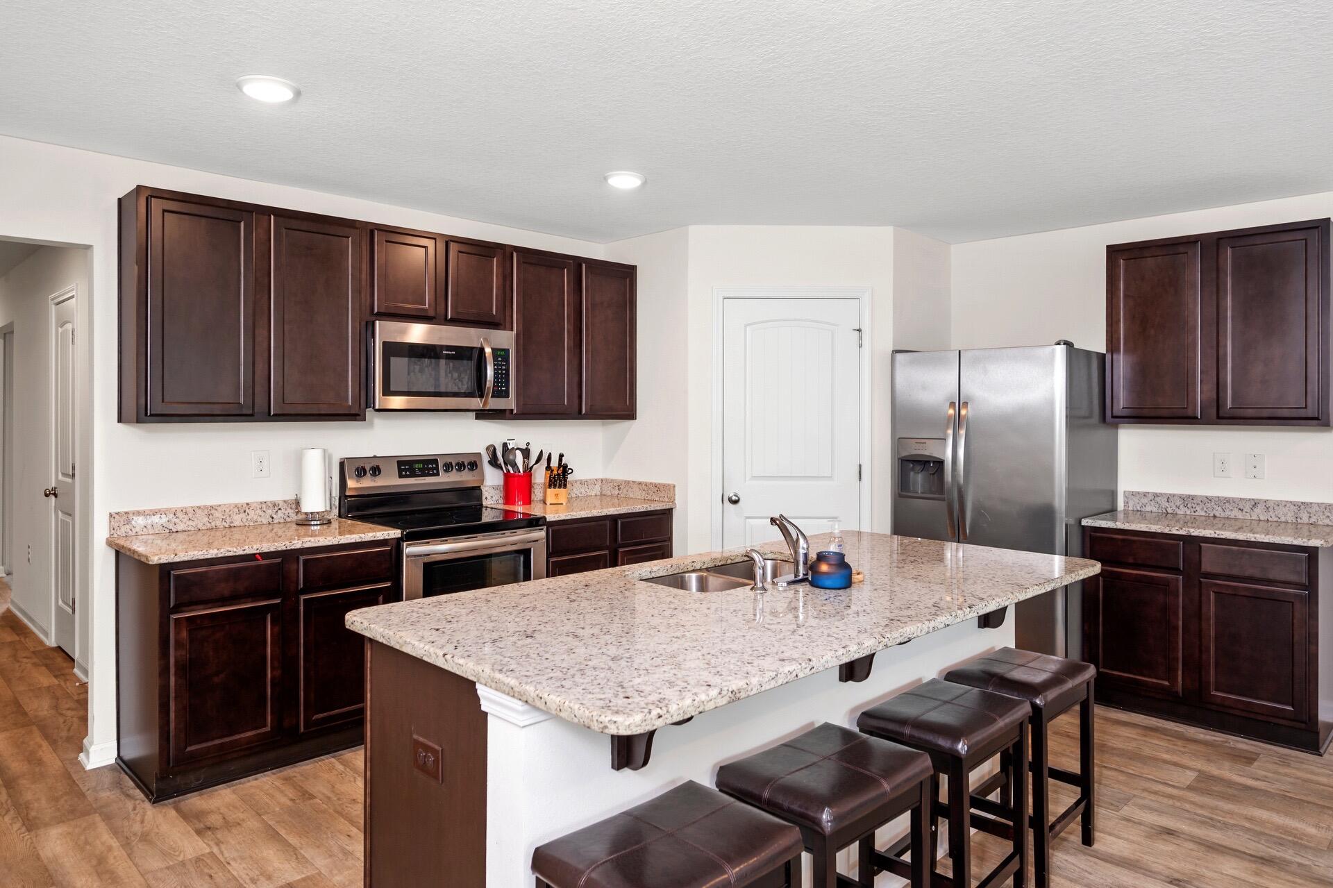 816 Moorhen Way Crestview, FL 32539 - Photo 10 of 22 a kitchen with granite countertop a stove refrigerator and microwave with wooden floor