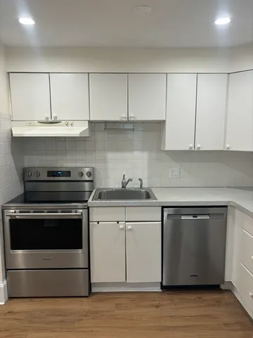 a kitchen with granite countertop white cabinets and a stove