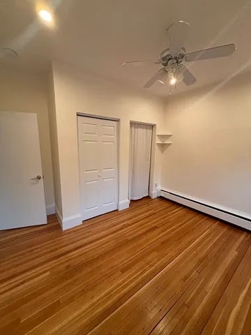 wooden floor in an empty room with a chandelier fan