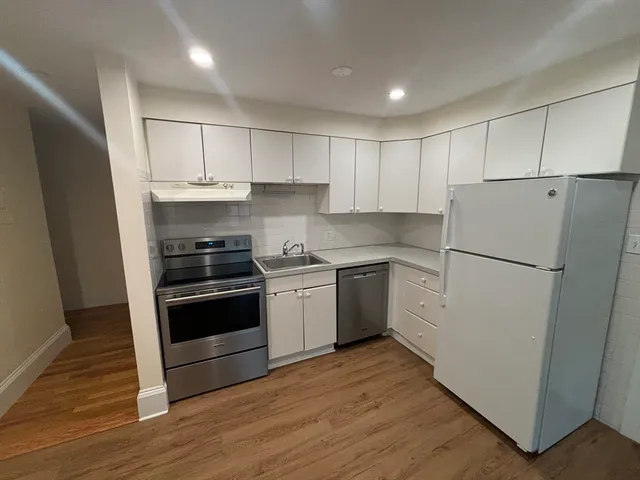 a kitchen with a refrigerator a stove top oven and white walls