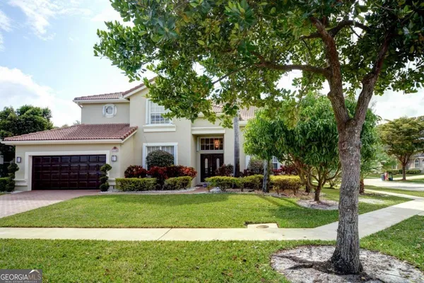 a front view of a house with a yard and tree