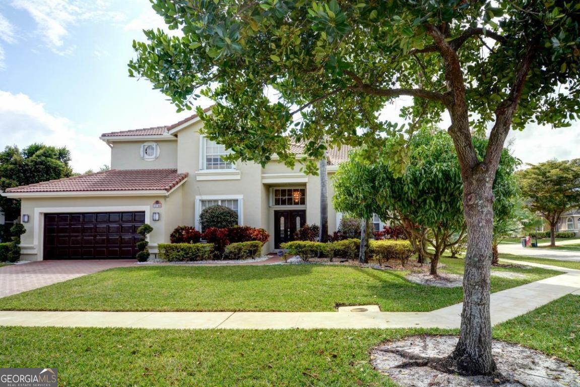 a front view of a house with a yard and tree