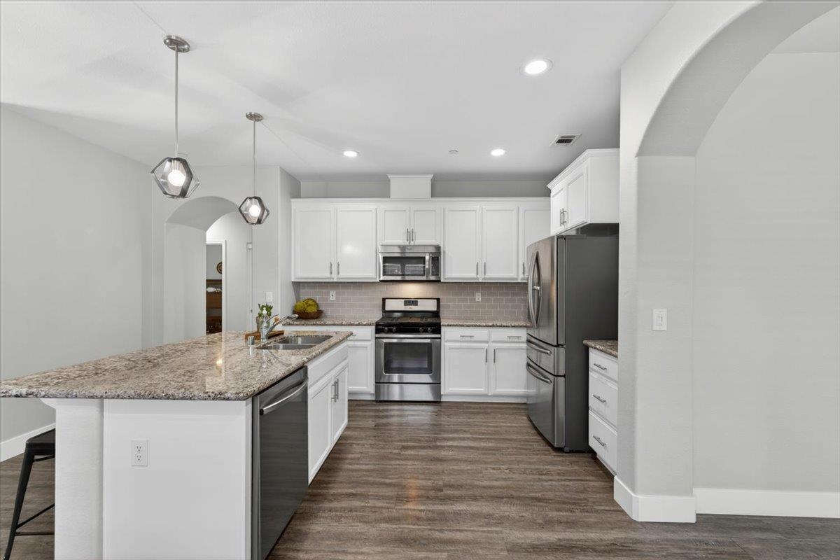 437 Silver Ridge Court Oakdale, CA 95361 - Photo 10 of 41 a large kitchen with stainless steel appliances granite countertop a stove a sink dishwasher a refrigerator white cabinets and wooden floor