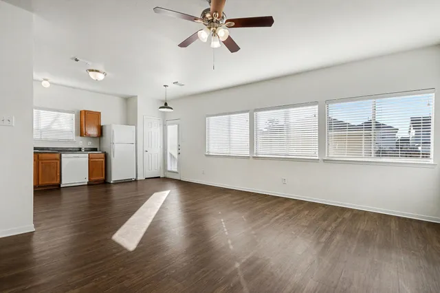a view of an empty room with a window and wooden floor