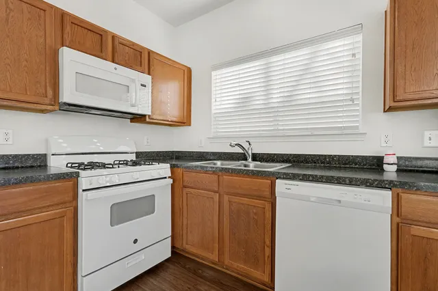 a kitchen with granite countertop white cabinets and white appliances