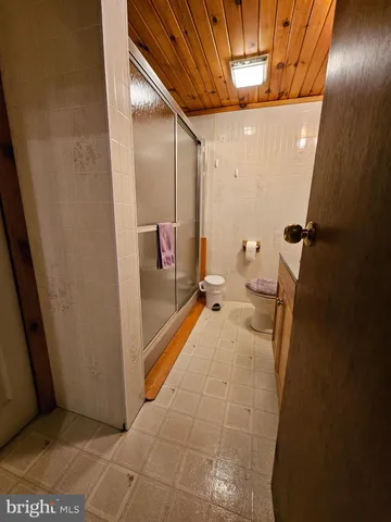 a bedroom with a bed a couch and wooden floor