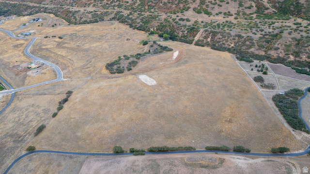 South Preserve Drive Mapleton, UT 84664 - Photo 2 of 11 Expansive open land with undulating terrain, featuring scattered natural greenery and a paved road bordering the perimeter