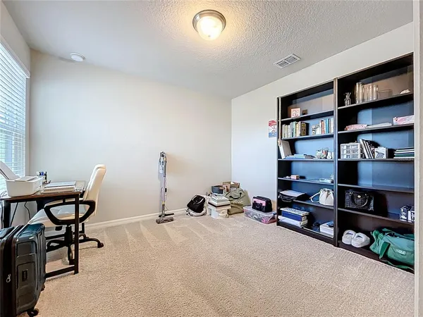 an empty room with a chandelier fan and windows