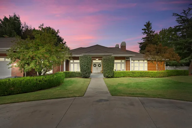 a front view of a house with a yard and trees