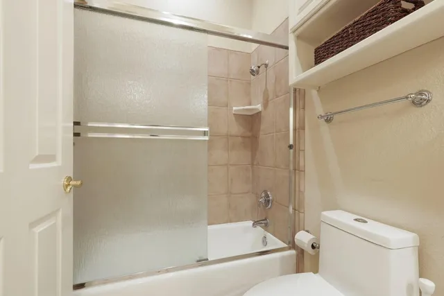 a view of a white house in front of a big yard with plants and large trees