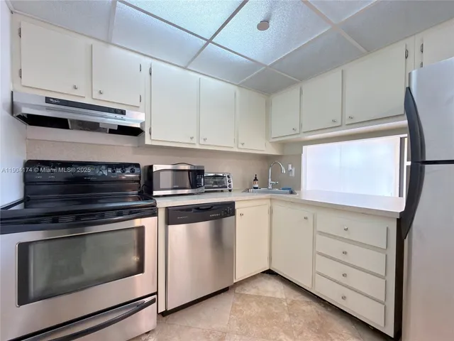a kitchen with stainless steel appliances granite countertop a refrigerator sink and white cabinets