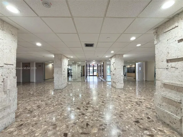 a view of an empty room with a window and kitchen view