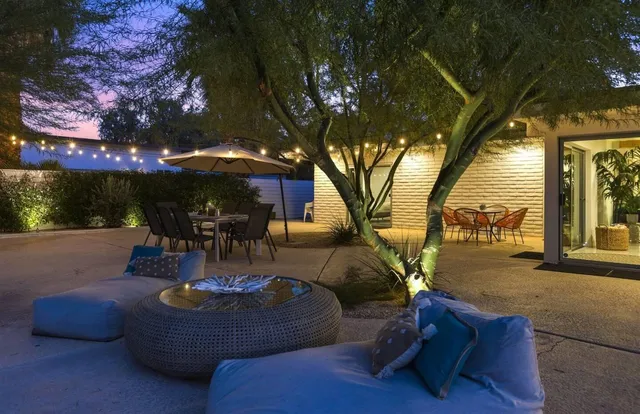 a view of lawn chairs and table under an umbrella in backyard