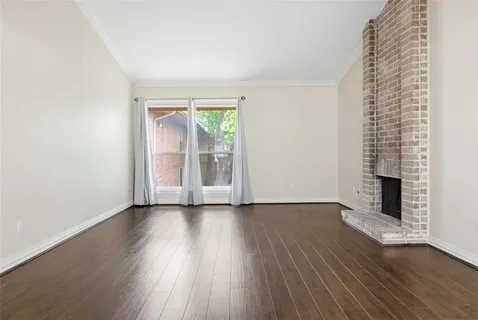 an empty room with wooden floor fireplace and windows